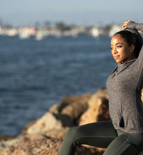 Silhouette of a woman stretching against a sunrise, feeling energetic.